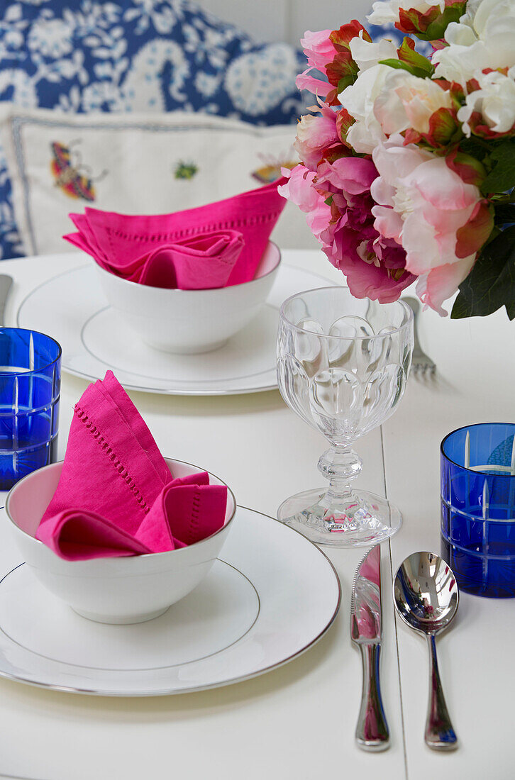 Bright pink napkins in bowls with cut flowers on table in London townhouse, England, UK