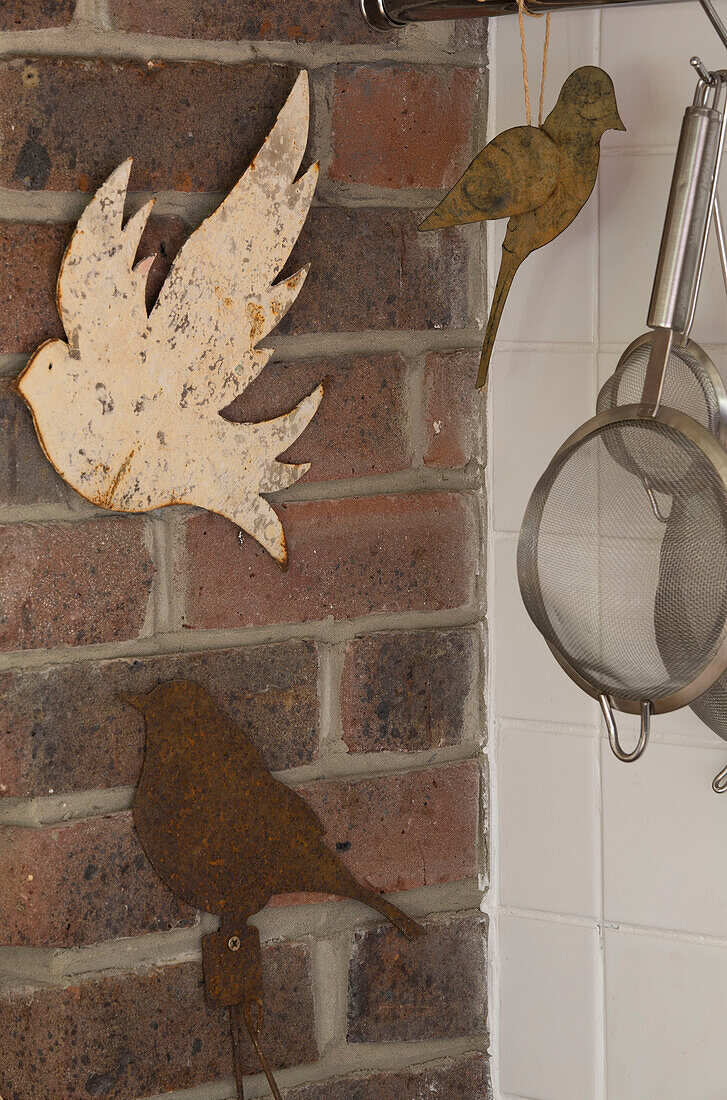 Metal birds and exposed brick in farmhouse kitchen, UK