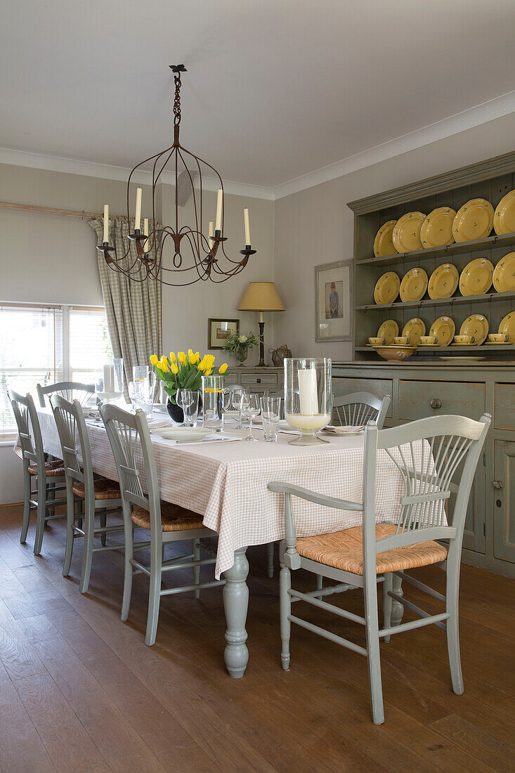 yellow plates on kitchen dresser in dining room set with table for eight in UK farmhouse