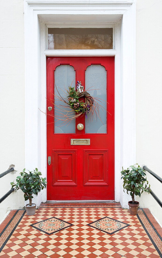 Weihnachtsgirlande an der leuchtend roten Eingangstür eines Londoner Hauses, England, Vereinigtes Königreich