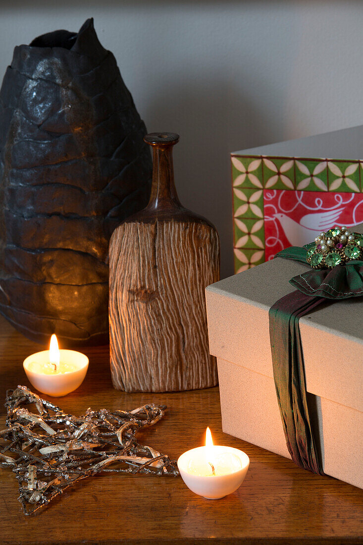 Lit tealights with gift box and carved wooden bottle in London home, England, UK