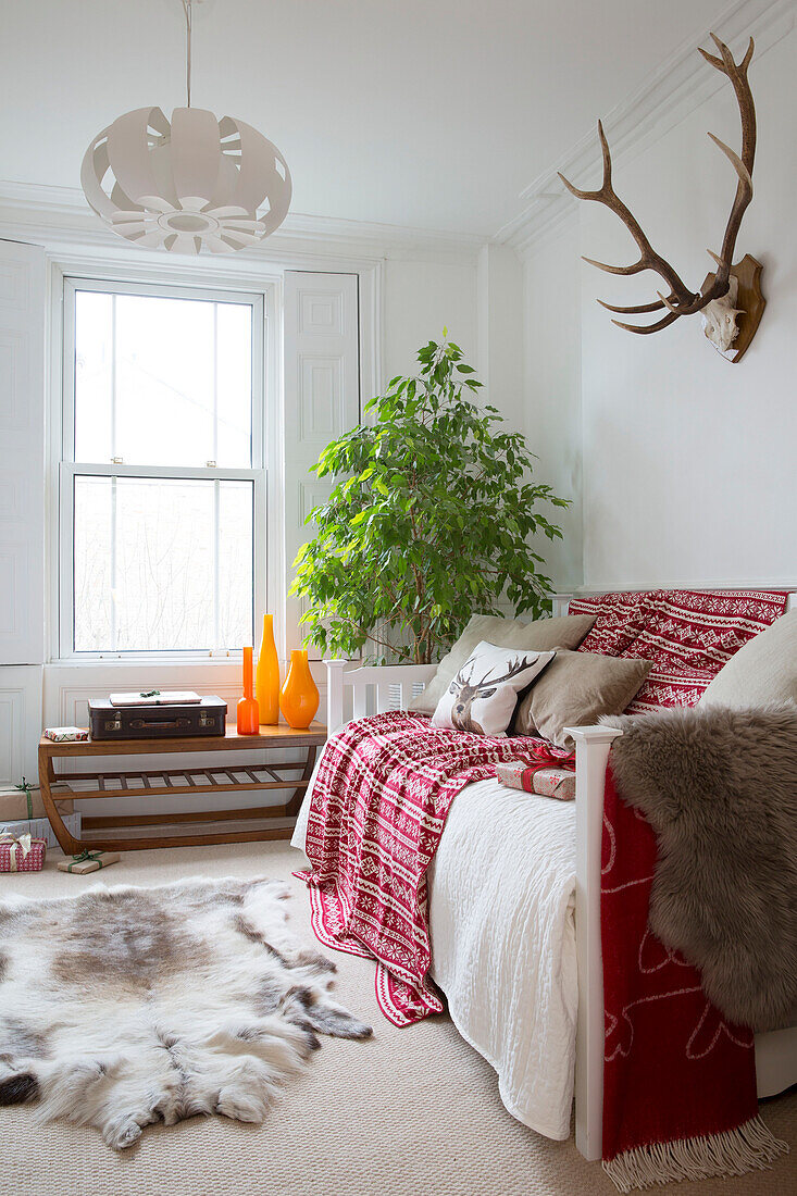 Geweih über einem Sofa mit Tierfell im Wohnzimmer eines Hauses in London, England, Vereinigtes Königreich
