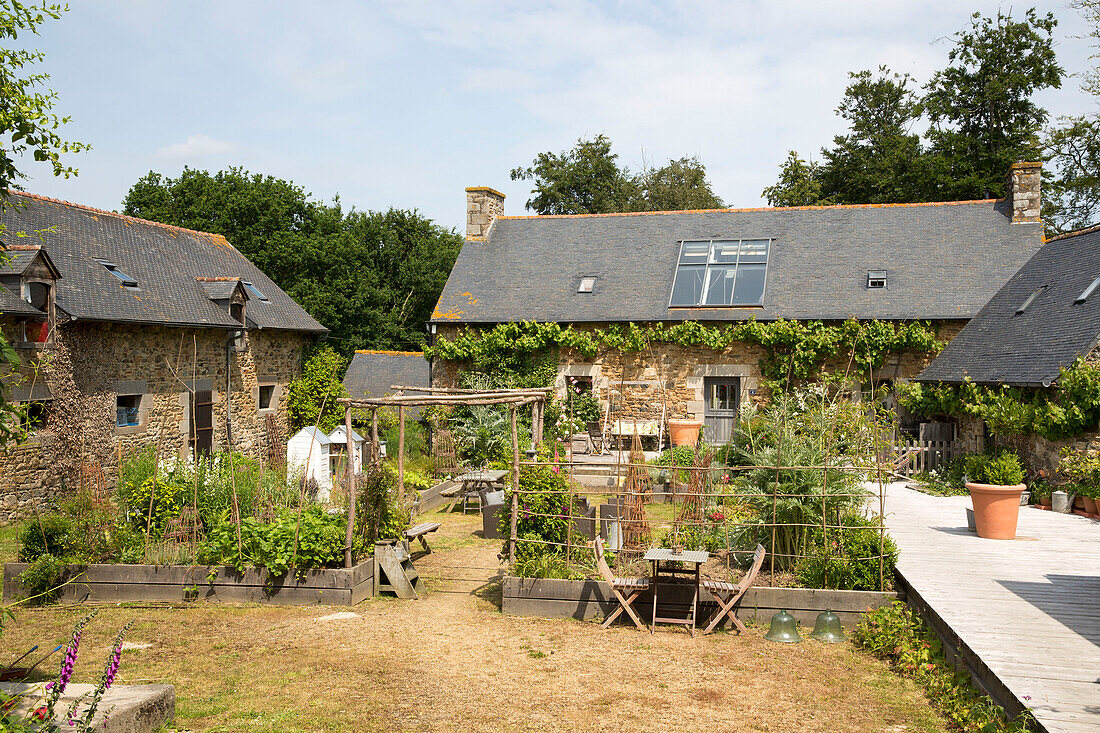 Küchengarten mit Terrassenbereich an der Außenseite eines französischen Bauernhauses