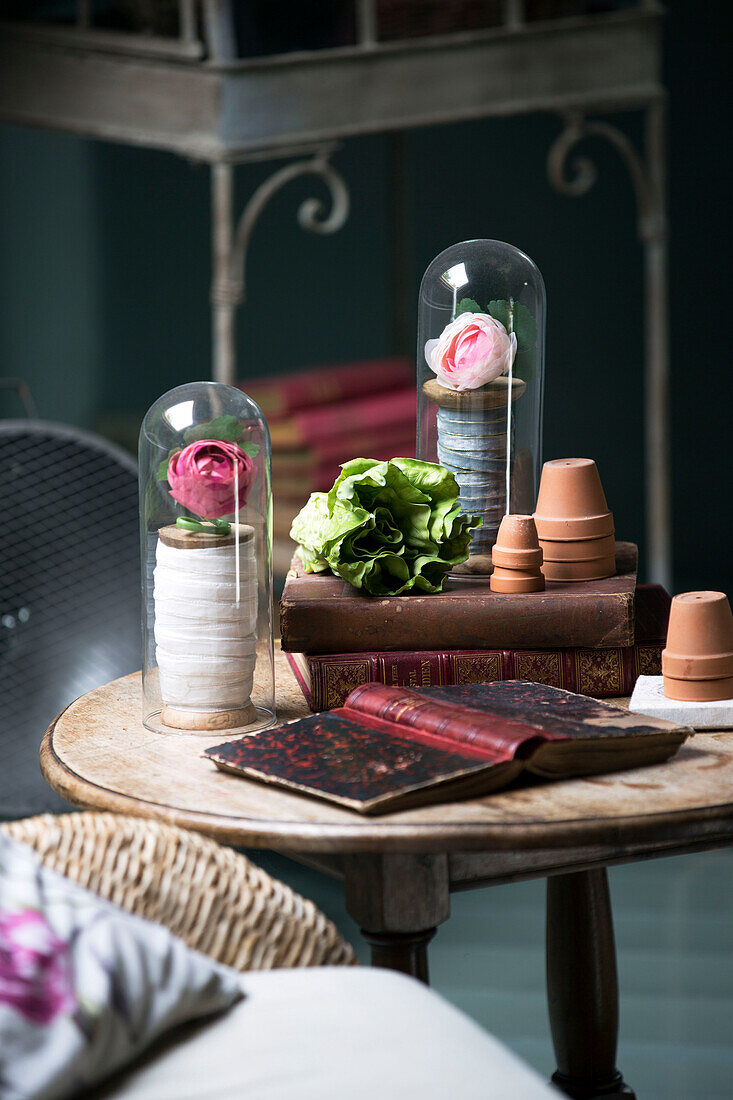 Gebundene Bücher mit Rosen in Vitrinen auf einem Holztisch in einem französischen Bauernhaus
