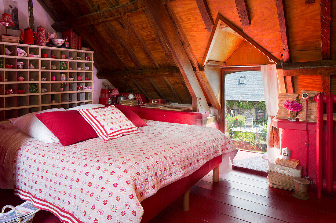 Geblümte Steppdecke auf einem Doppelbett mit Ablagefächern an einer Dachgaube in einem französischen Bauernhaus
