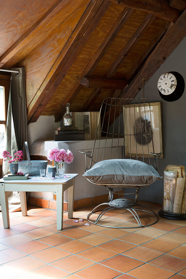Large velvet cushion on vintage metal chair under wooden ceiling in French farmhouse