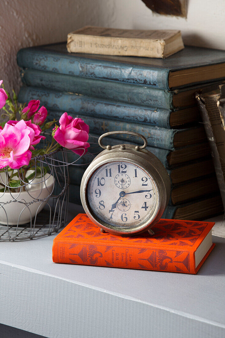 Antiker Wecker auf gebundenem Buch mit Schnittblumen in einem französischen Bauernhaus