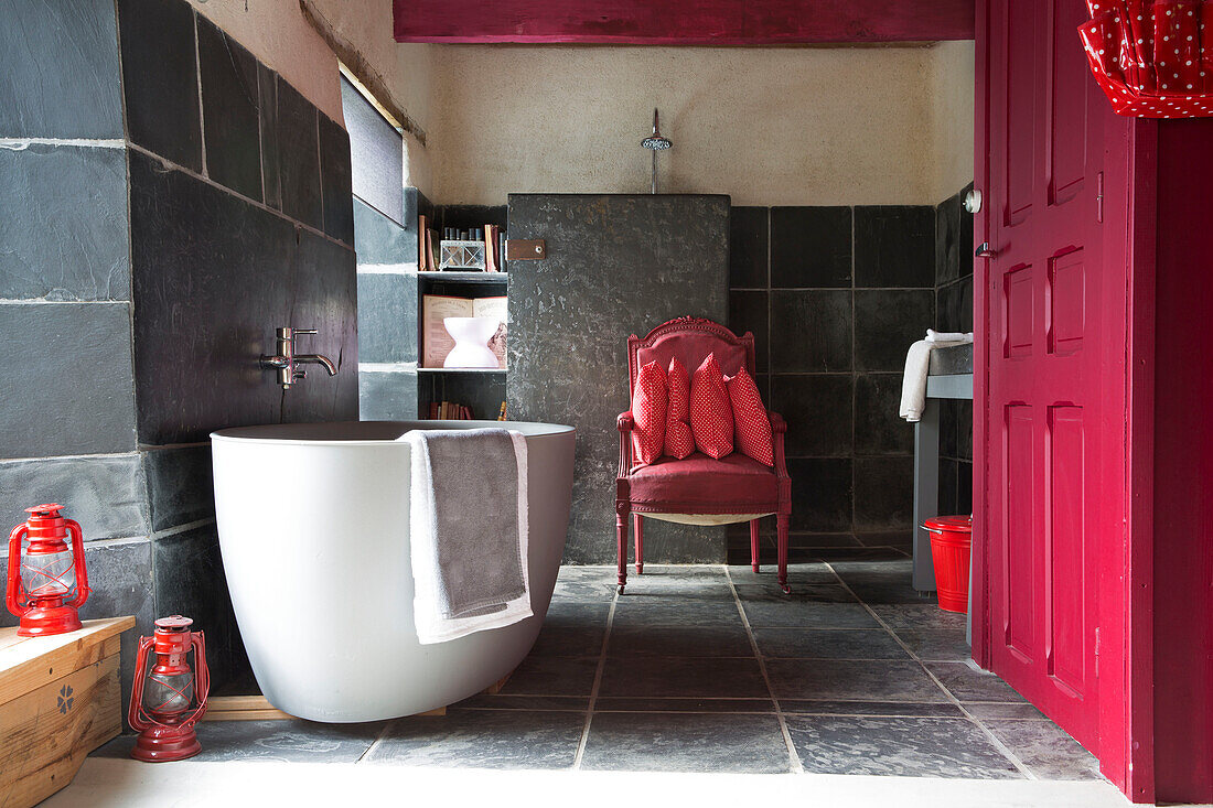 Freestanding bath with red paintwork in bathroom tiled with slate, Brittany cottage, France