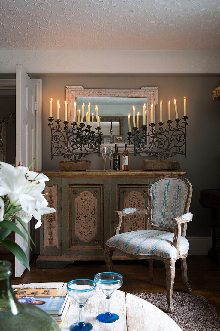 Gepolsterter Stuhl mit bemalter Anrichte und schmiedeeisernem Kerzenständer in einer britischen Wohnung