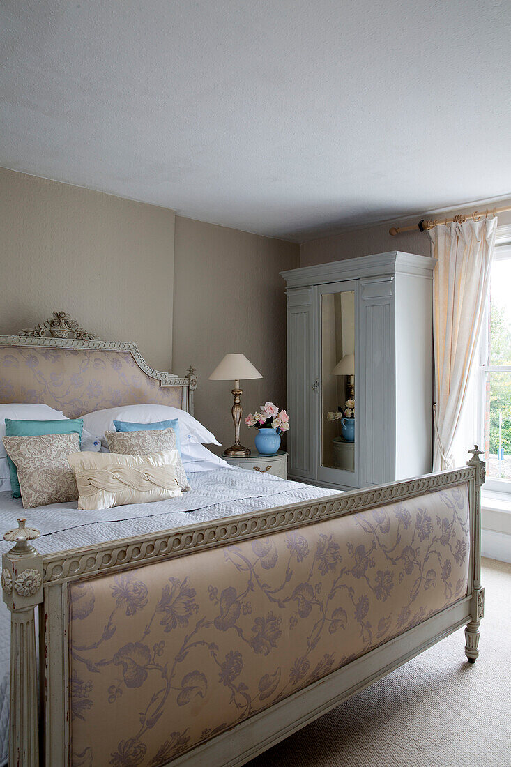 Gemalter Kleiderschrank und Doppelbett in einem Zimmer mit Gardinen und Raffhalter in einem Haus in Großbritannien