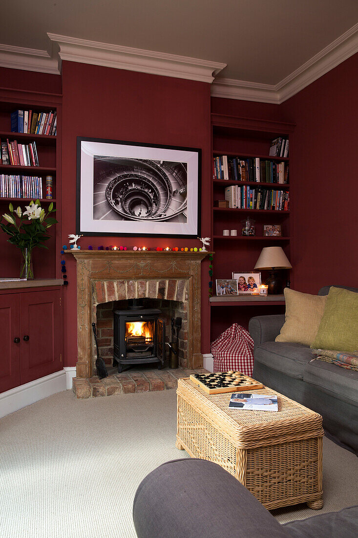 Graues Sofa vor beleuchtetem Kamin im Wohnzimmer mit eingelassenen Regalen in Shoreham by Sea home West Susses England UK