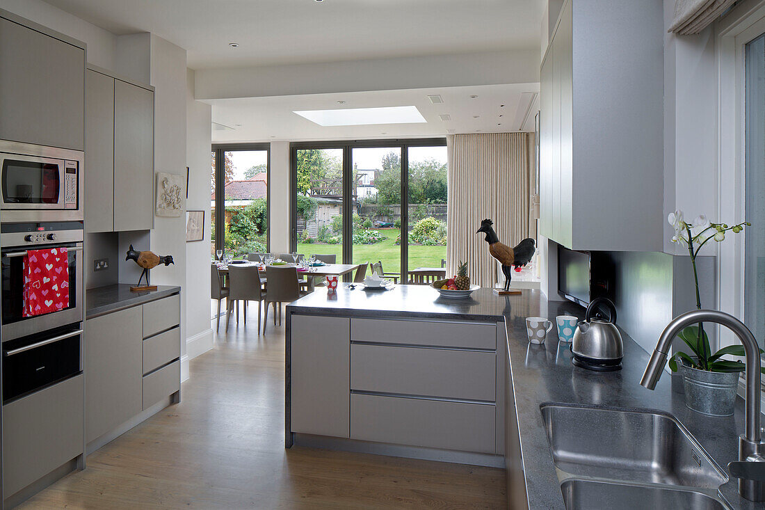 Offene Einbauküche und Esszimmer mit Blick durch Terrassentüren in den Garten eines Hauses in Großbritannien