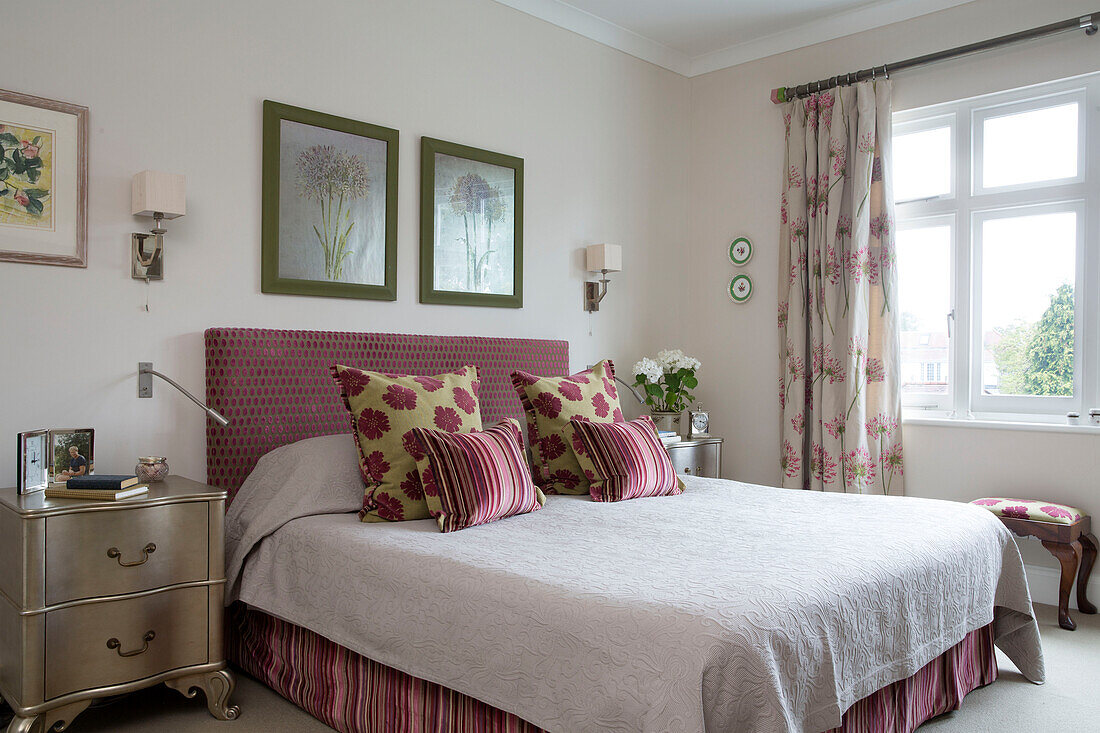 Gemusterte Kissen mit gepolstertem Kopfteil auf einem Doppelbett mit goldfarbenem Nachttisch in einer britischen Wohnung