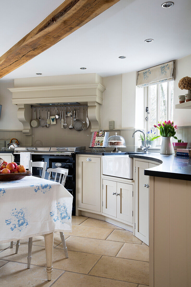 Geschwungene weiße Einbauküche mit Geschirrleiste über dem Ofen in einem Bauernhaus in Suffolk, England, UK