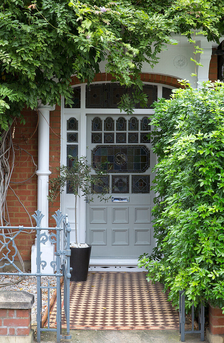 Von Pflanzen überwucherte Buntglasfronttür eines Hauses in Hertfordshire, England, Vereinigtes Königreich