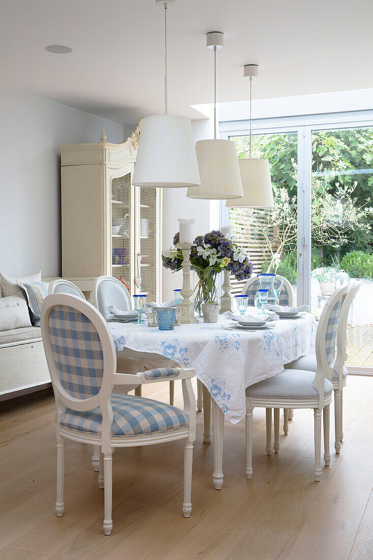 Karierte Esszimmerstühle um den Tisch mit weißen Hängelampen in einem Haus in Hertfordshire, England, UK