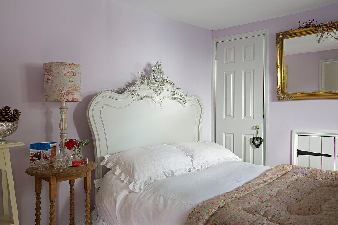 Double bed with quilt and gilt-framed mirror in lilac bedroom of Berkshire home,  England,  UK