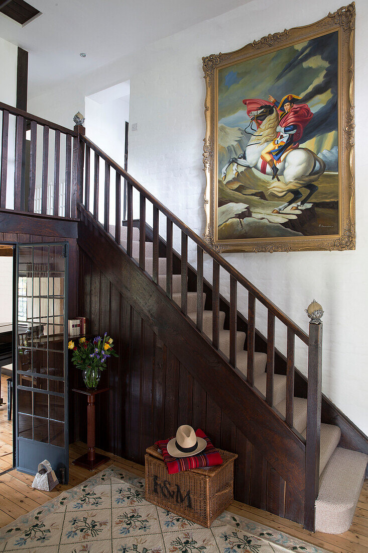 Großes gerahmtes Kunstwerk über der Holztreppe im Eingangsbereich eines Cottages in Sussex, England, UK