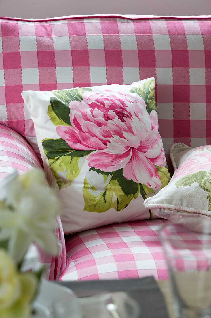Floral cushion on pink gingham sofa in Sussex cottage   England   UK