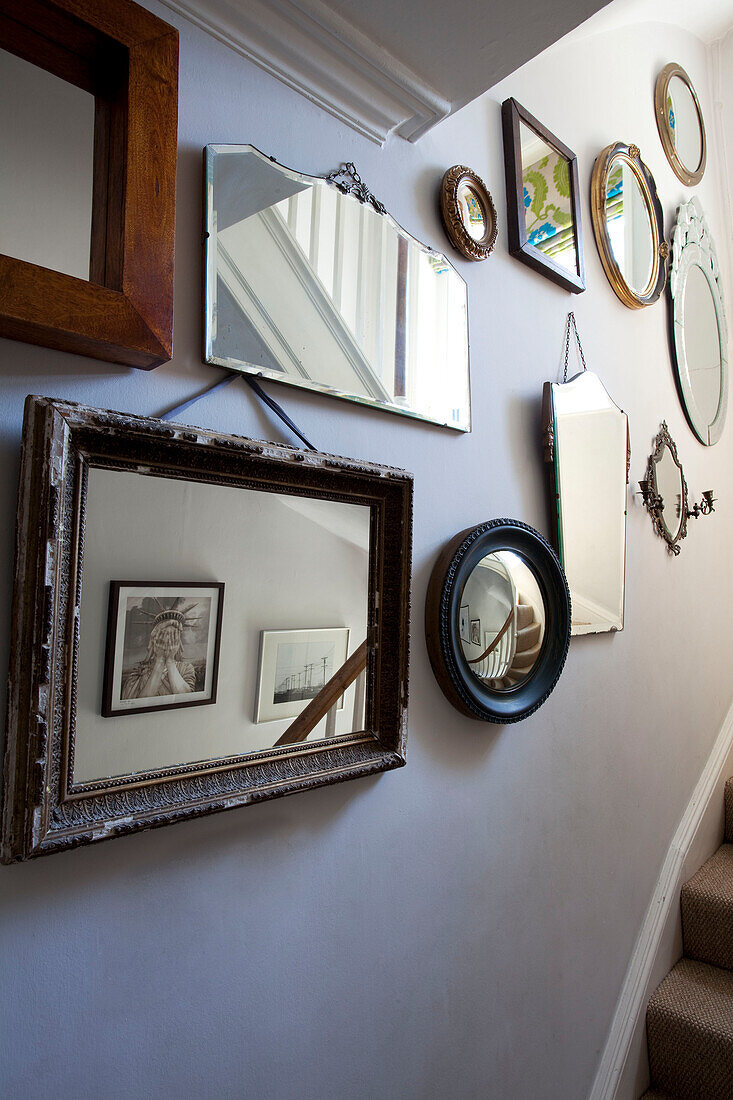 Assorted vintage mirrors on wall in staircase of London townhouse, England, UK