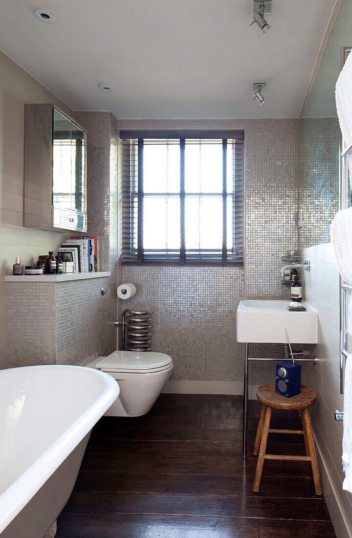 Mosaic tiled bathroom with wooden floorboards in London townhouse, England, UK