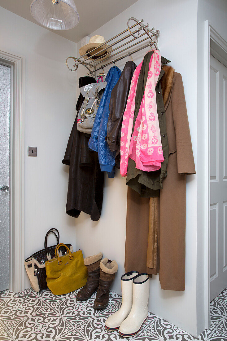 Mäntel und Schals mit Stiefeln und Taschen auf einem Regal im Flur eines Londoner Hauses, England, UK