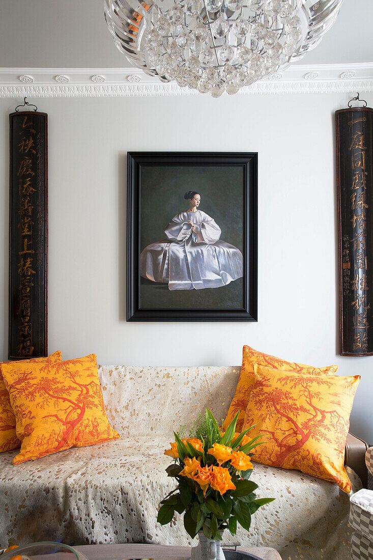Chinese calligraphy and artwork above sofa with yellow patterned cushions in London home, England, UK