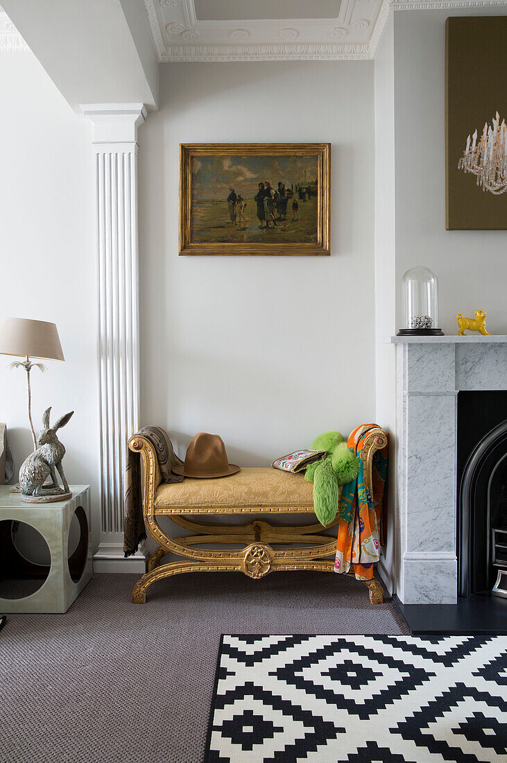 Hut auf Bank unter goldgerahmtem Kunstwerk im Wohnzimmer eines Londoner Hauses, England, UK