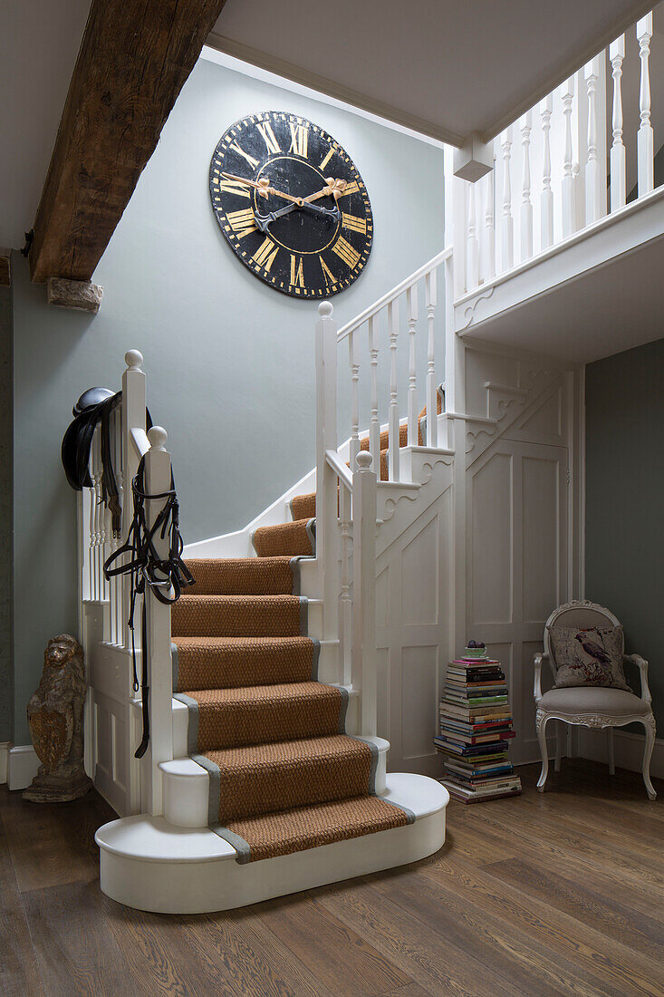 Sattel und Zaumzeug auf Geländer in Sussex Treppenhaus mit großer schwarzer Uhr UK