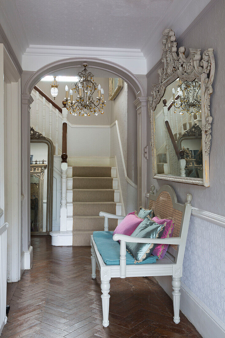 Sitzbank mit dekorativem Spiegel im Parkettflur eines Hauses in Großbritannien