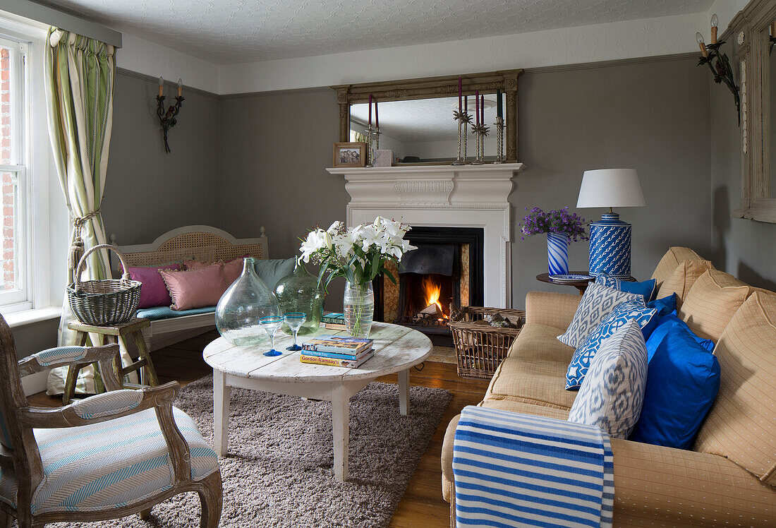 Gestreifte blaue Decke auf gelbem Sofa im Wohnzimmer mit Couchtisch in einem Haus in Großbritannien