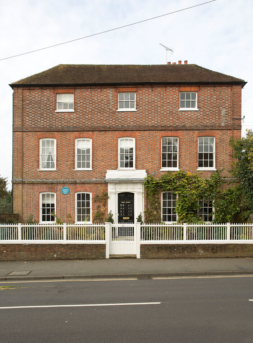 Dreistöckiges freistehendes Backsteinhaus in Surrey mit weißem Lattenzaun, England, UK