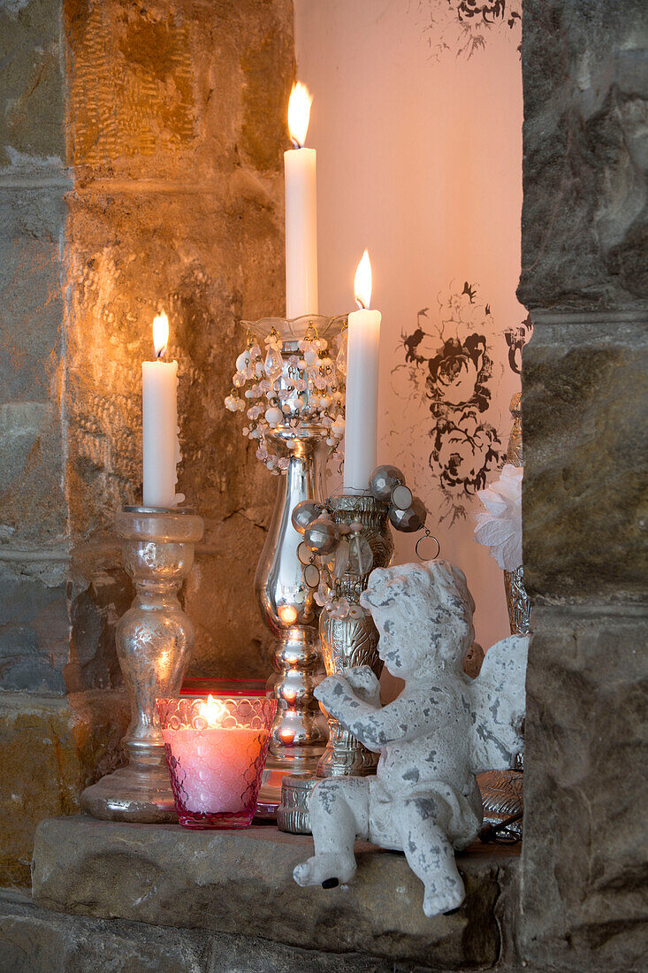 Lit candles with statue of cherub on recessed stone alcove in Laughton home  Sheffield  UK
