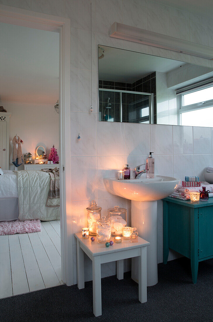 Beleuchtete Kerzen auf einem Beistelltisch mit einem Waschbecken unter einem Spiegel im eigenen Badezimmer im Haus Laughton Sheffield UK