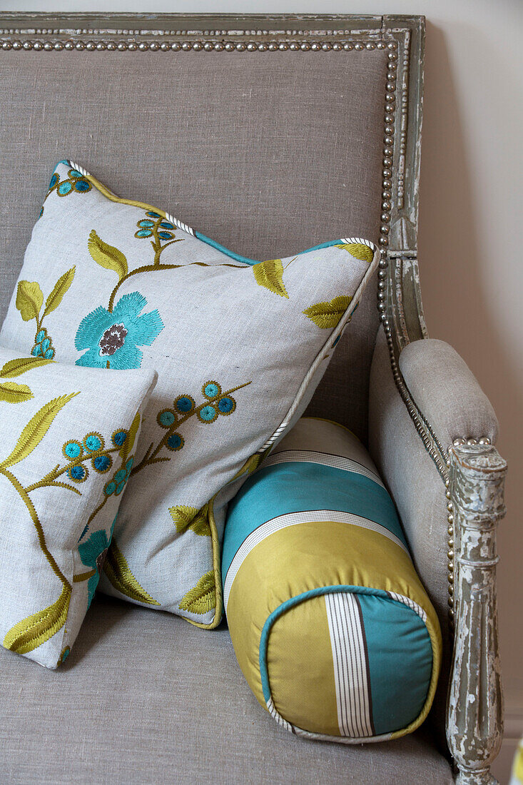 Floral embroidered cushions on grey armchair in London home   England   UK