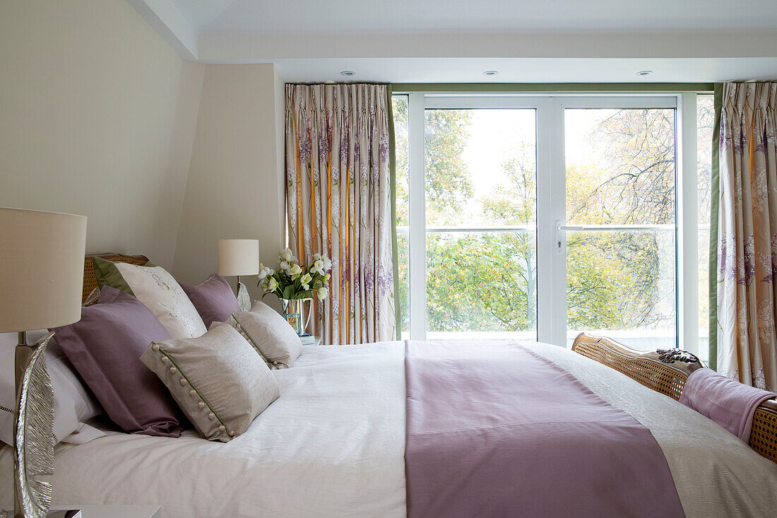 Fliederfarbene Seide auf einem Doppelbett mit cremefarbenen Lampenschirmen am Fenster eines Londoner Hauses England UK