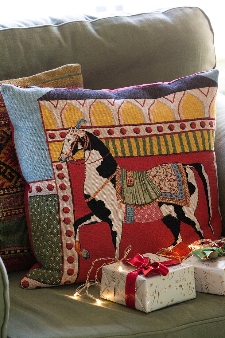 Equestrian cushion and gift-wrapped presents on armchair in Sussex living room  England  UK