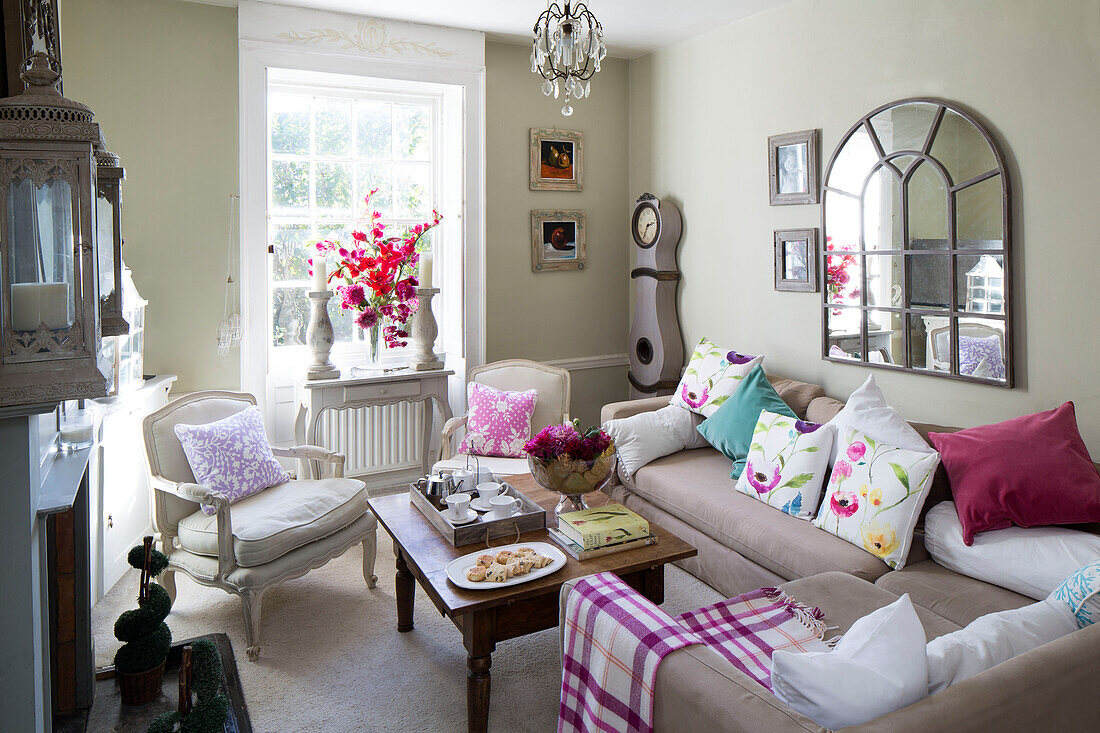 Arched mirror above corner sofa in sunlit living room of Berkshire home,  England,  UK