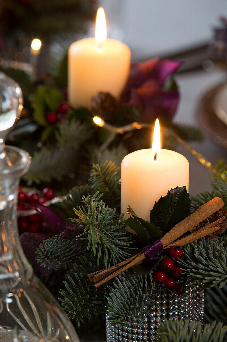 Beleuchtete Kerzen mit Zimtstangen in einem Haus in Chobham zu Weihnachten Surrey England UK