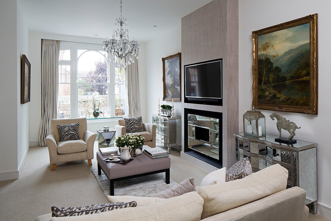 Glaskronleuchter im Wohnzimmer mit Bogenfenster und goldgerahmten Kunstwerken in einem modernen Londoner Haus UK