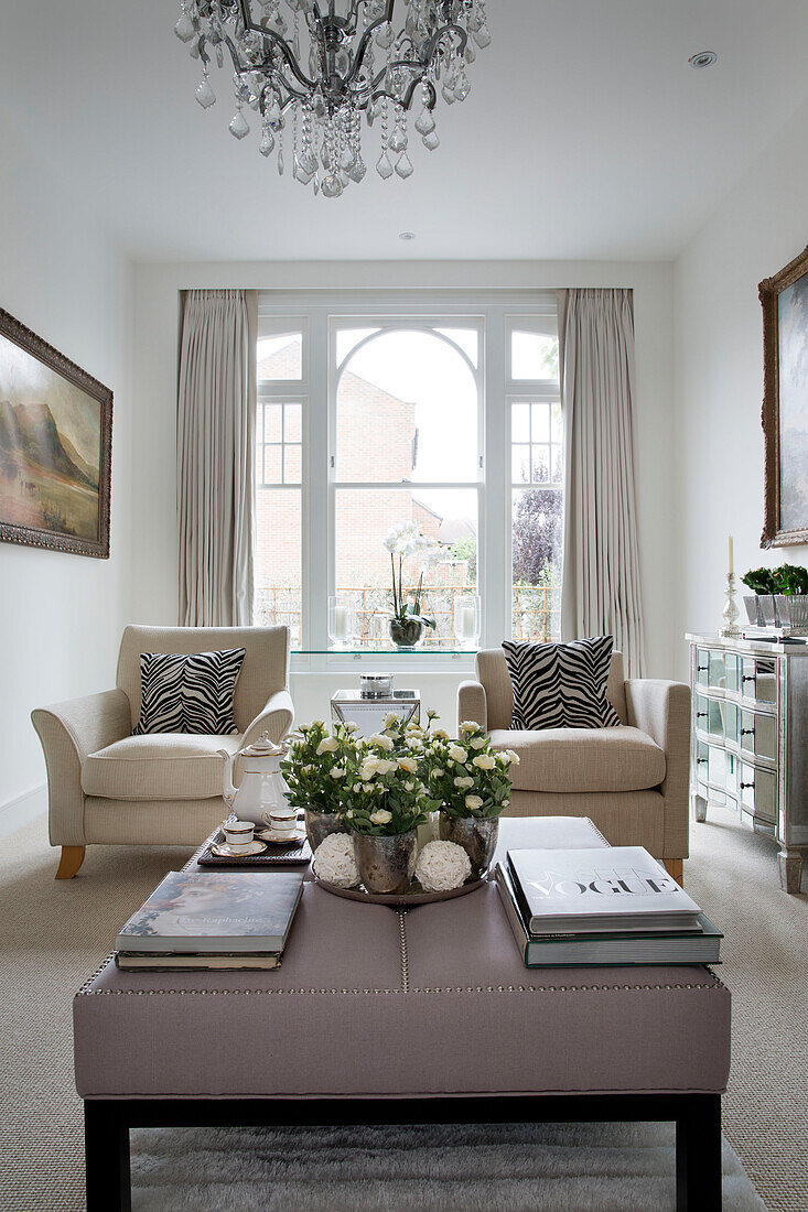 Paar Sessel und Ottomane im Wohnzimmer mit Bogenfenster in einem modernen Londoner Haus UK