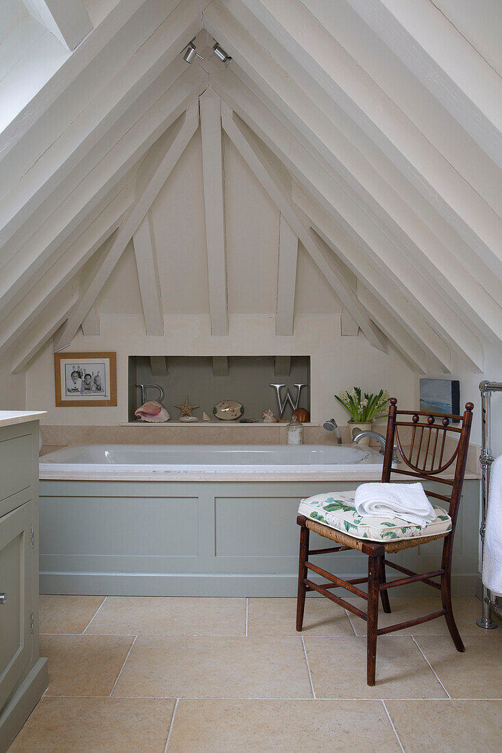 Holzstuhl mit Sitzkissen im Dachgeschoss-Badezimmer eines britischen Bauernhauses