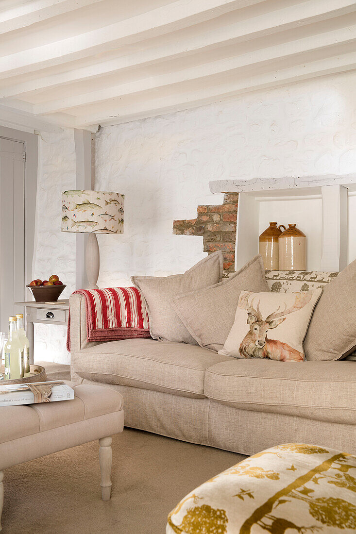 Freigelegtes Mauerwerk mit Hirschkissen auf Sofa in Wohnzimmer mit Holzbalken in einem Londoner Haus, England, UK