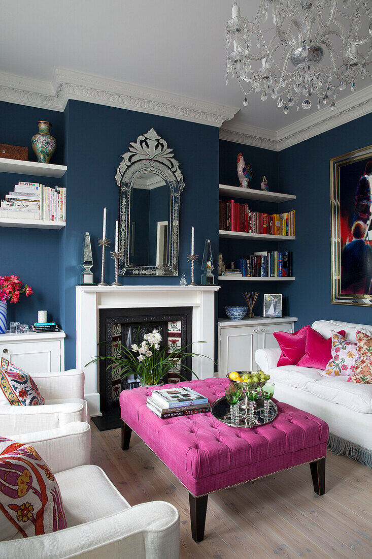 Kristallkronleuchter über rosa Ottomane im blauen Wohnzimmer eines Londoner Hauses, England, UK