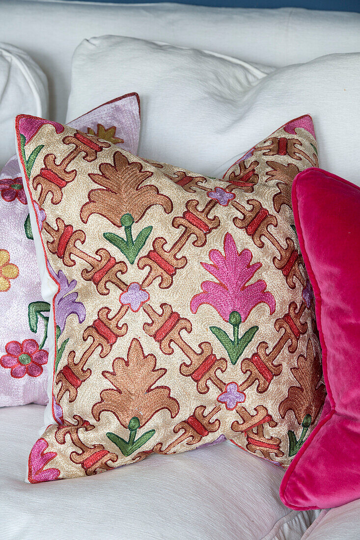 Brightly patterned cushions on white sofa in London home,  England,  UK