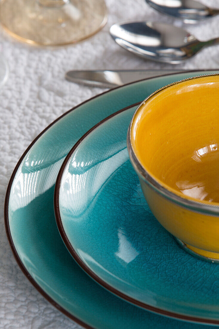 Gelbe Schleife auf türkisfarbenen Tellern auf einem Esstisch in einem Londoner Haus, England, UK