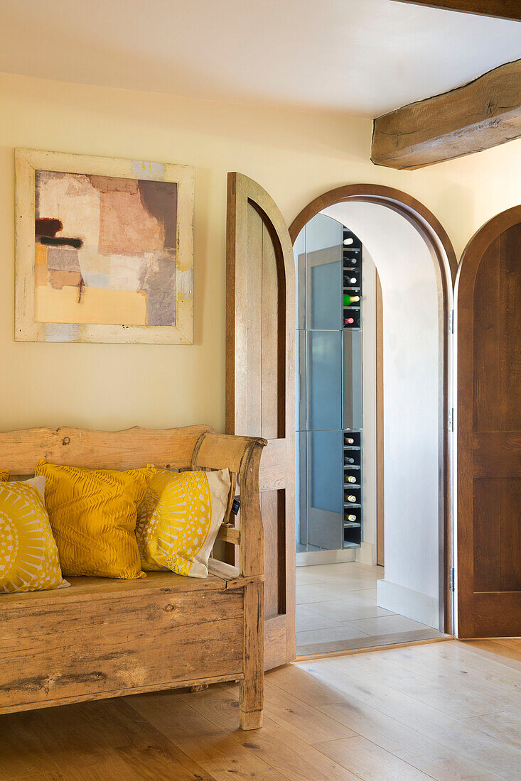 Holzsofa mit modernem Kunstwerk und gewölbter Doppeltür in Sandhurst Landhaus Kent England UK