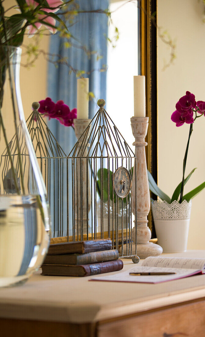 Drahtuhr und Kerzenständer mit Orchidee auf Anrichte in Sandhurst Landhaus Kent England UK