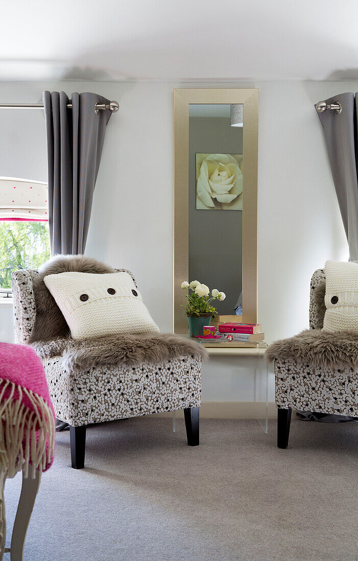 Ein Paar passender Stühle mit Wollkissen und Fellüberwürfen im Schlafzimmer von Sandhurst, Kent England UK