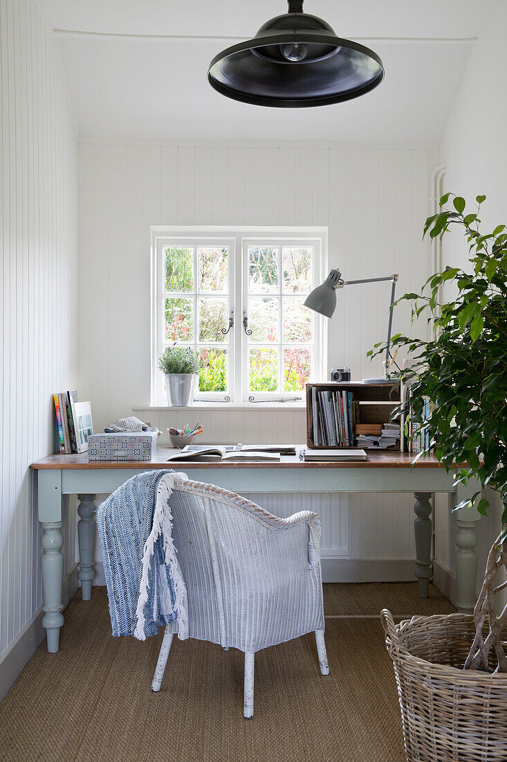 Korbstuhl am Schreibtisch unter dem Fenster im Haus in East Dean, West Sussex UK